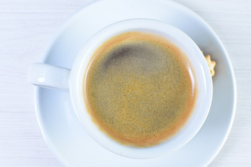 Cup of espresso coffee with coffee beans on white wooden background