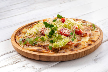 Italian pizza Caesar with chicken and bacon on a white wooden background..