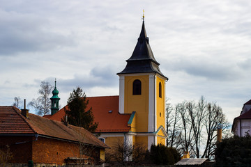 Beautiful medieval Czech church tower behind leafless trees. Czech Republic