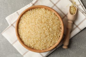 Bowl with rice, towel and spoon on grey background, top view