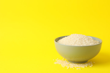 Bowl with rice on yellow background, space for text