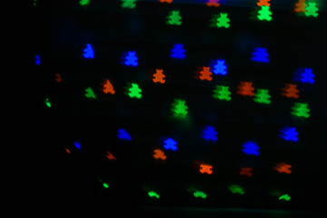 Bokeh in the form of bears of different colors on a dark background