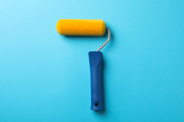 Paint roller on blue background, space for text