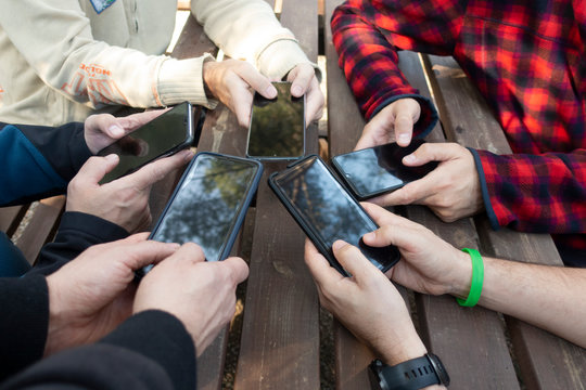 group of friends manipulating mobile phones at a picnic table