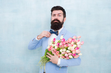 Happy womens day. Bearded man hold spring flowers. Tulip bouquet for womens day. Hipster wear formal suit and bowtie. Ready for womens day celebration. March 8. International womens holiday