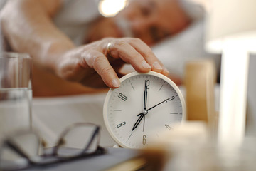Close-up of senior man turning off alarm clock.