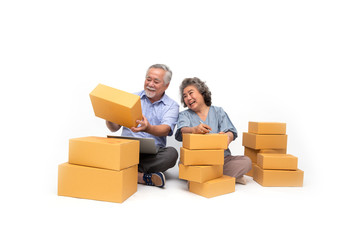 Senior asian couple startup small business freelance holding parcel box and computer laptop and sitting on floor isolated on white background, Online marketing packing box delivery concept