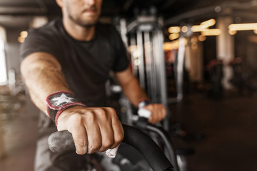 Close up on hands of fit young man using exercise bike at the gym