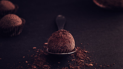 Close up of belgian truffles with cocoa powder on wood table black background