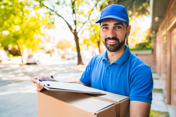 Delivery man carrying package outdoors.