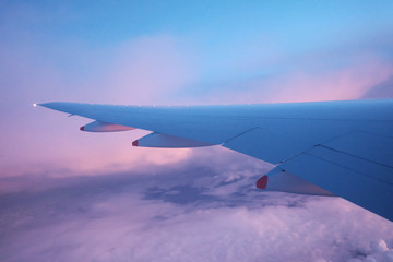 Fototapeta na wymiar Colorful fluffy clouds and dawn sky with blurred an airplane wing and beautiful high view from a plane window 