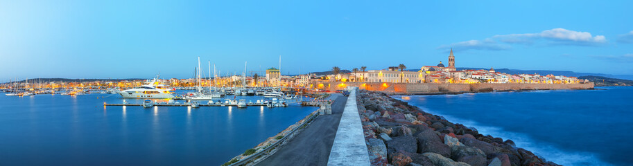 Obraz premium Panoramic evening cityscape of Alghero port and historical part of cit