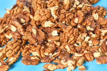 Heap of pieces of pulp and whole walnut on blue background