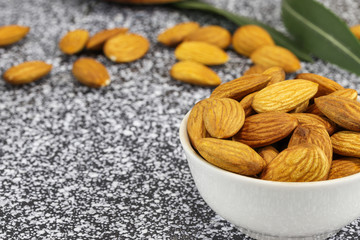 White bowl with almonds on a black and white marble surface