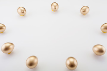 Golden eggs are laid out around the place for the dough, on a white background, with copy space. Concept backgrounds for Easter, a symbol of wealth and abundance, finance.