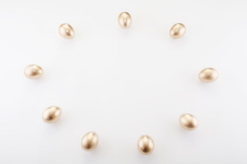 Golden eggs are laid out around the place for the dough, on a white background, with copy space. Concept backgrounds for Easter, a symbol of wealth and abundance, finance.
