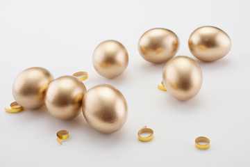 Golden eggs with a gold ribbon on a white background. Concept photo for Easter.