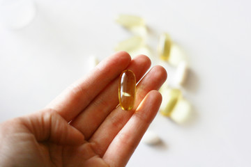 Womens hand is holding a pill. Tablets and pills laying on table. Background for pharmacology. Medicament composition.