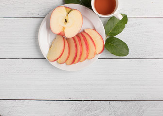 Giant apple and leaves with a cup of tea on a white ship lap background ready for your cllean diet
