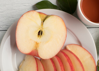 Giant apple close up and leaves with a cup of tea on a white ship lap background ready for your cllean diet