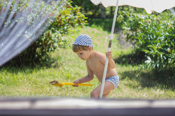 A child sticks a beach umbrella in the ground