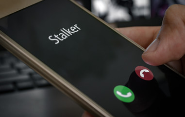 Stalker caller. A man holds a phone in his hand and thinks to end the call. Incoming from an unknown number at work. Incognito or anonymous, scammer or stranger - obrazy, fototapety, plakaty