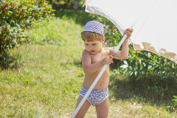 A child sticks a beach umbrella in the ground