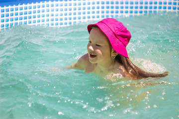 Little girl happily splashes in the water on a sunny day.