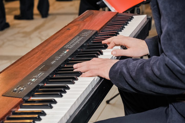 hands on black and white keys of a musical instrument,a man plays the keys close up