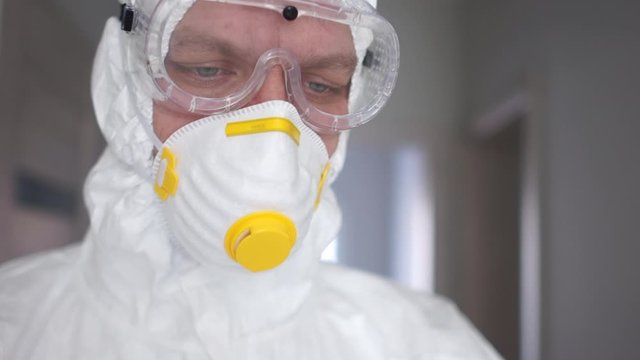 Medic in a protective suit and mask is preparing to do an injection close portrait. Pandemic threat, coronavirus treatment, coronavirus vaccine