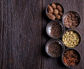 Set of various spices on rustic wood background. Pepper, turmelic, paprika, basil, rosemary, chilly, cardamom, cinnamon, anise. Top view with copy space.
