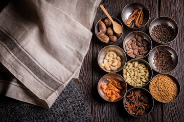 Set of various spices on rustic wood background. Pepper, turmelic, paprika, basil, rosemary, chilly, cardamom, cinnamon, anise. Top view with copy space.