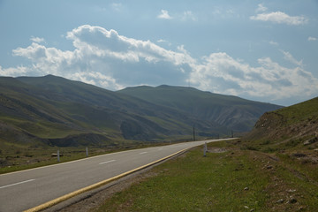 Winding country road in mountains . Asphalt road in the mountains with soft sky on the background. yellow and white line