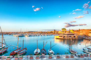 Fototapeta na wymiar Summer view of the Alghero Marina yacht port at the Gulf of Alghero with anchored sailboats