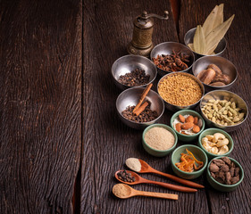 Set of various spices on rustic wood background. Pepper, turmelic, paprika, basil, rosemary, chilly, cardamom, cinnamon, anise. Top view with copy space.