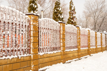 fence in the snow in the winter afternoon in the park