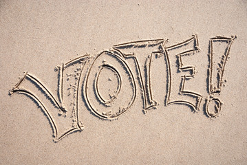 Simple VOTE! message spelled out on smooth sand beach