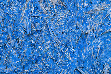 Blue abstract background with wooden texture. Painted OSB panel. detailed view of wood chip particle board building construction material in vivid blue colour.