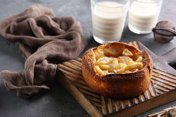 Apple pie with cinnamon on a wooden board. Glasses of milk and sieve near pie. Background image, copy space