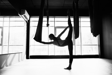 Silhouette of a beautiful young woman doing fly yoga