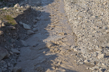 Stony river, high green mountains on the background. Rocks on river bed .The wild river stream has been working on stones for many years . Limestone riverbank. Running water in the river .