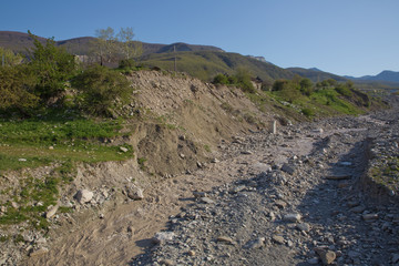 Stony river, high green mountains on the background. Rocks on river bed .The wild river stream has been working on stones for many years . Limestone riverbank. Running water in the river .