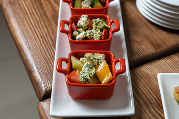 Organic caesar salad in red bowl with caesar dressing. Wooden table, luxury catering.