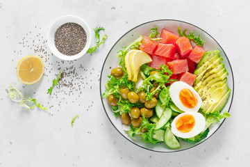 Ketogenic, keto or paleo diet lunch bowl with salted salmon fish, lemon, avocado, olives, boiled egg, cucumber, green lettuce salad and chia seeds. Healthy food trend. Top view