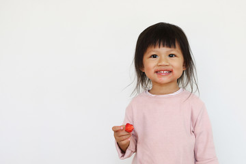 smiling asian girl enjoys eating red strawberry and having dirty face