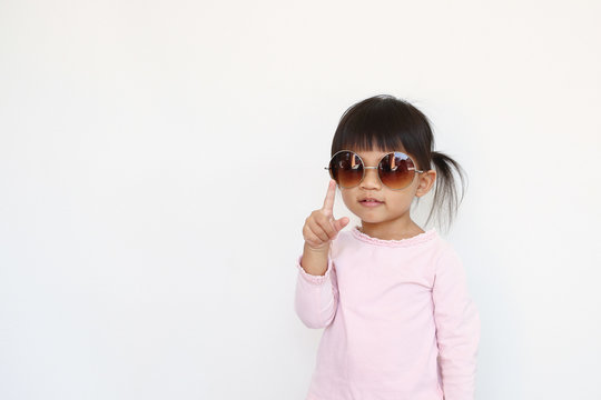 happy asian girl wears sunglasses and point in the air