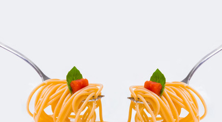 Mirrored fork holding spaghetti with tomato and basil