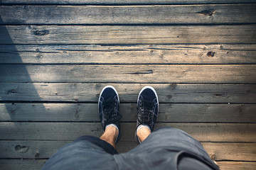 Top view of man legs with shoes on wooden floor.