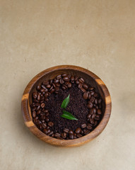 Homemade coffee scrub and two leaves on wooden table