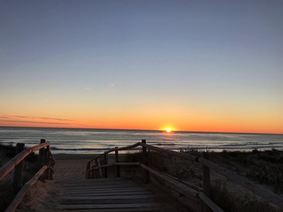 precioso atardecer en la playa con el mar mediterraneo en calma visto desde el puente de madera